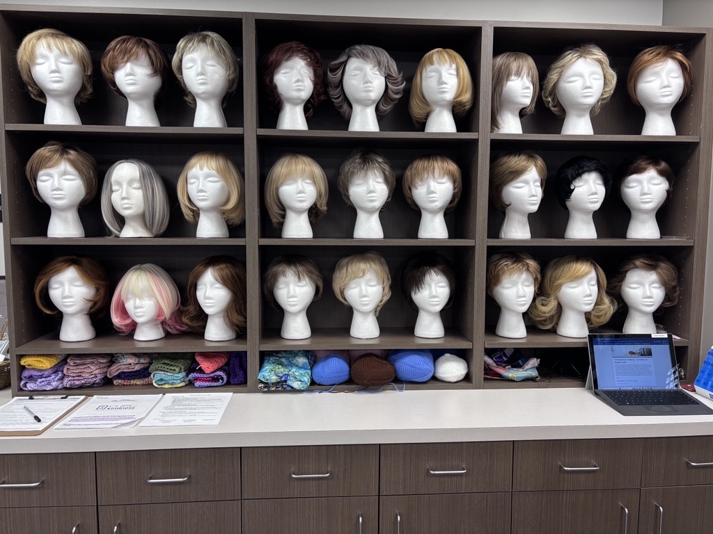 Shelves displaying wigs on styrofoam heads.